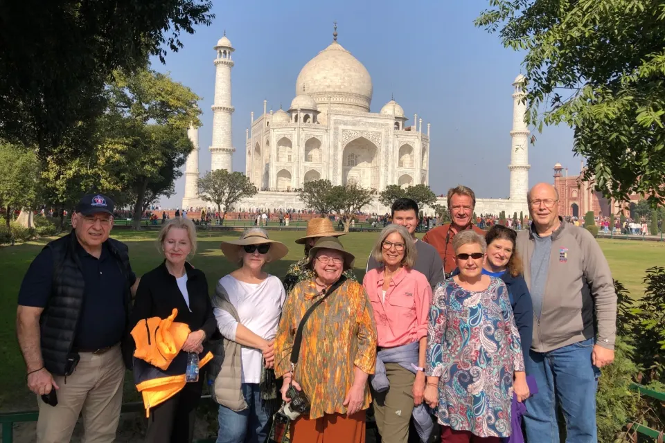 Group of visitors posing in the Taj Mahal gardens with minarets in the background