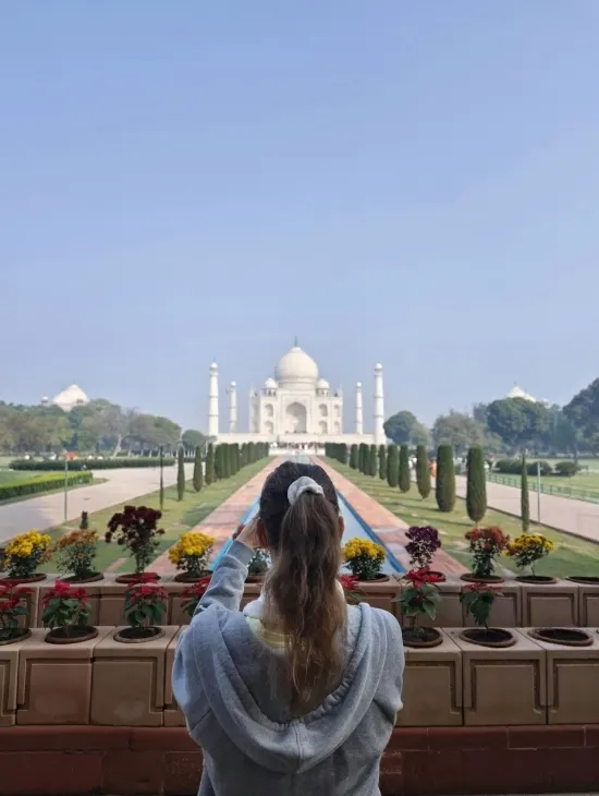Visitor holding up a phone to photograph the Taj Mahal with the domes centered behind