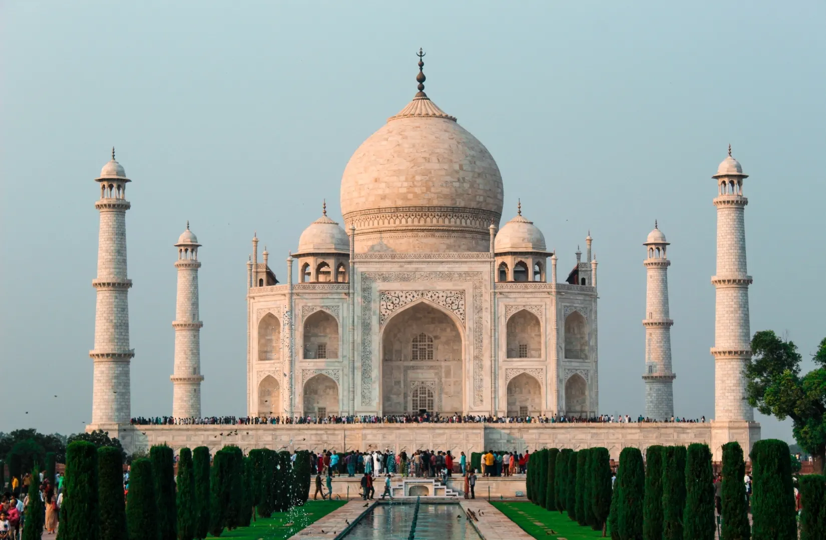 Taj Mahal reflected in the central water channel with crowds gathered at the platform