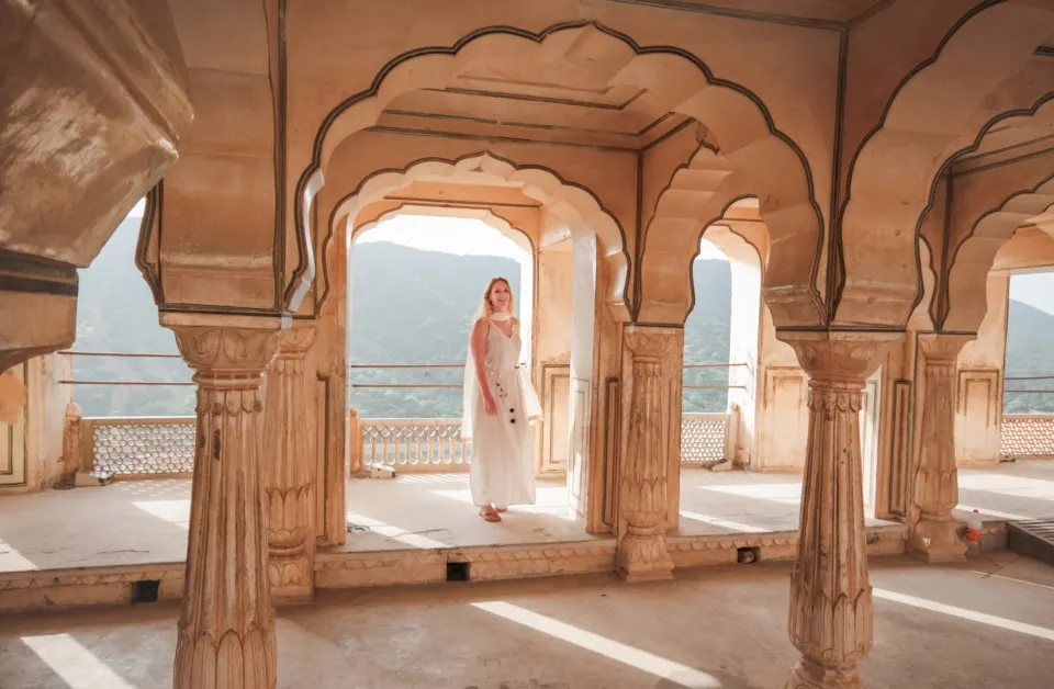 Traveler standing beneath scalloped arches inside an Amber Fort courtyard