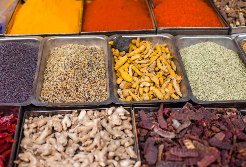 Assorted spices displayed in metal trays at a spice market in Old Delhi
