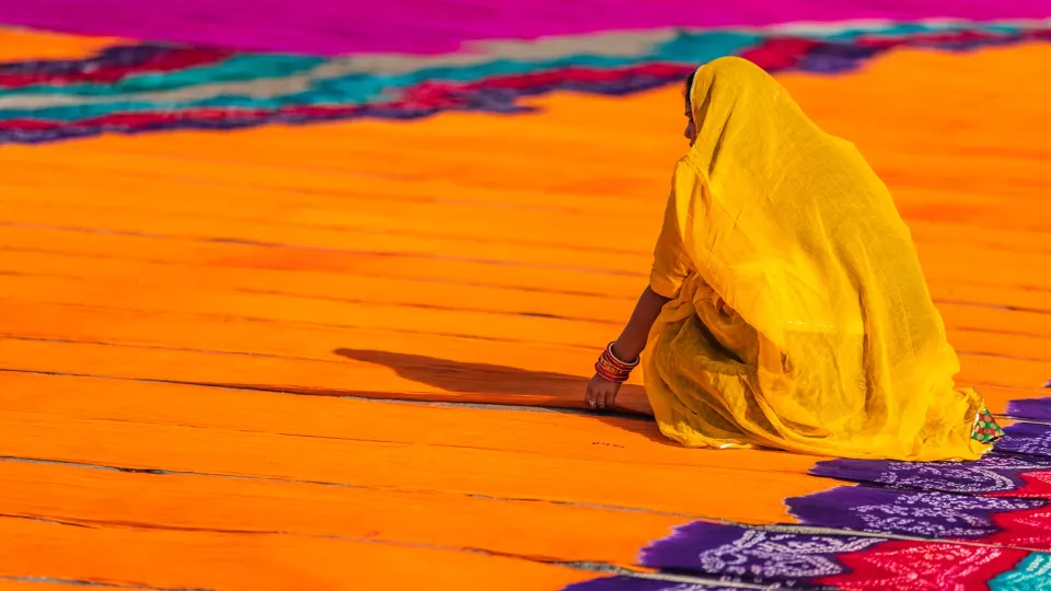 Woman sitting on hand dyed textiles laid out to dry