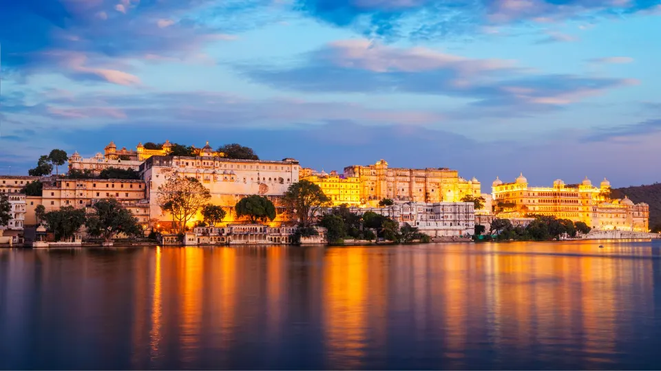 City Palace illuminated beside Lake Pichola at dusk