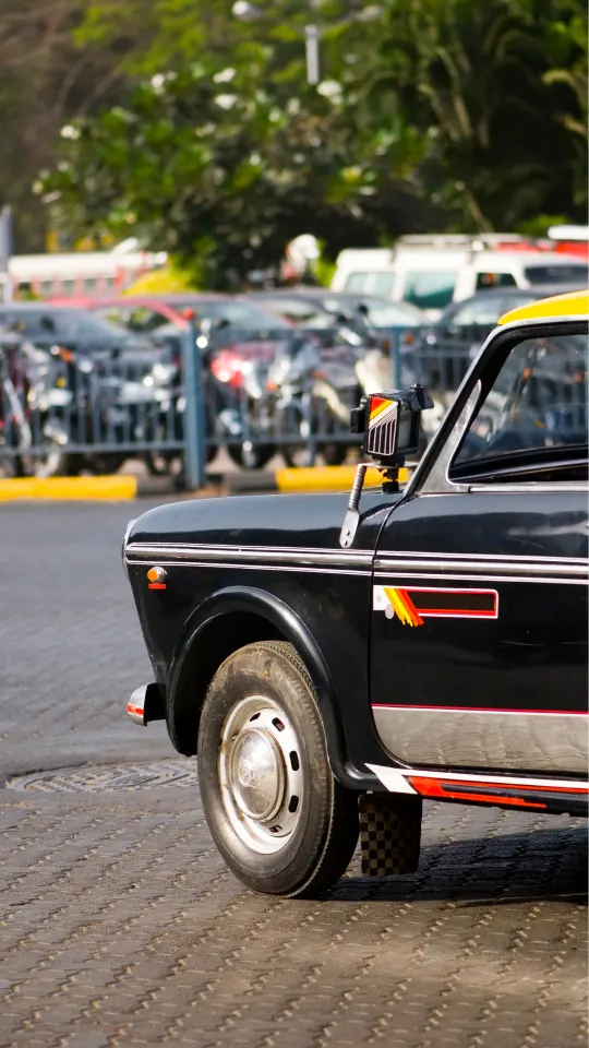 black and yellow mumbai taxi parked on city street