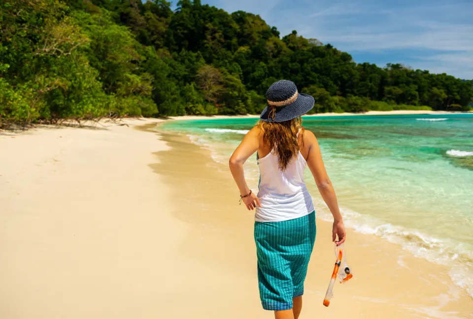 traveller walking along a quiet beach in havelock island