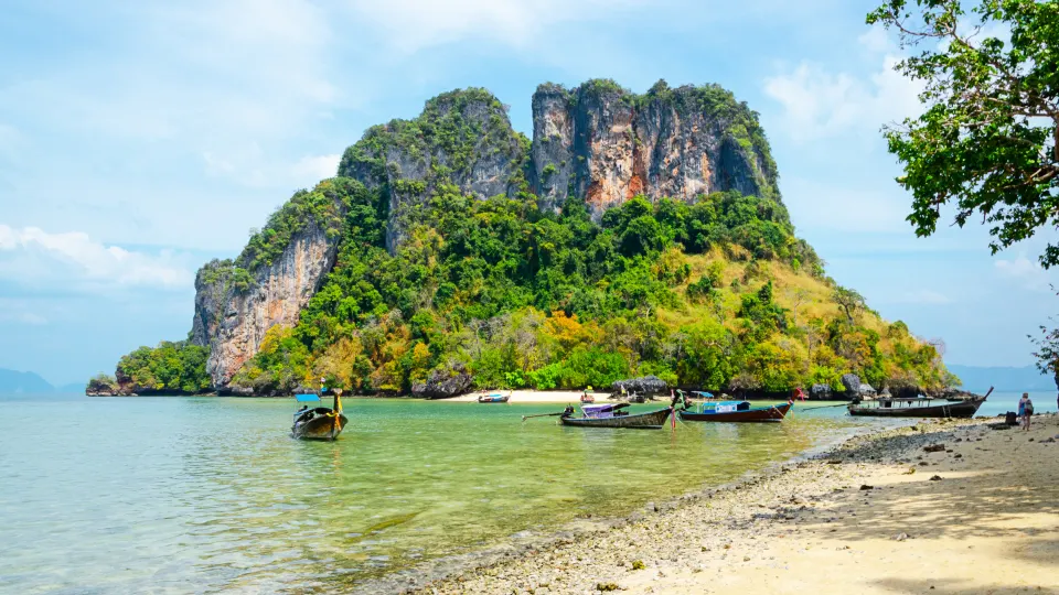 limestone islet rising from shallow sea with anchored wooden boats near ross island