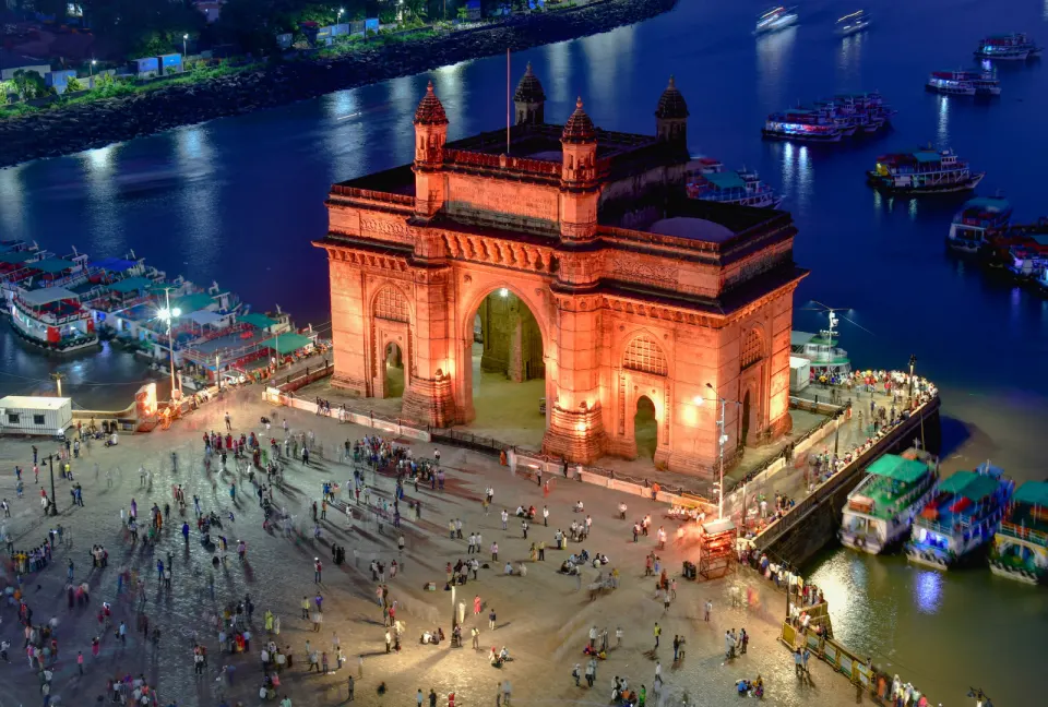 Aerial night view of the illuminated Gateway of India surrounded by boats