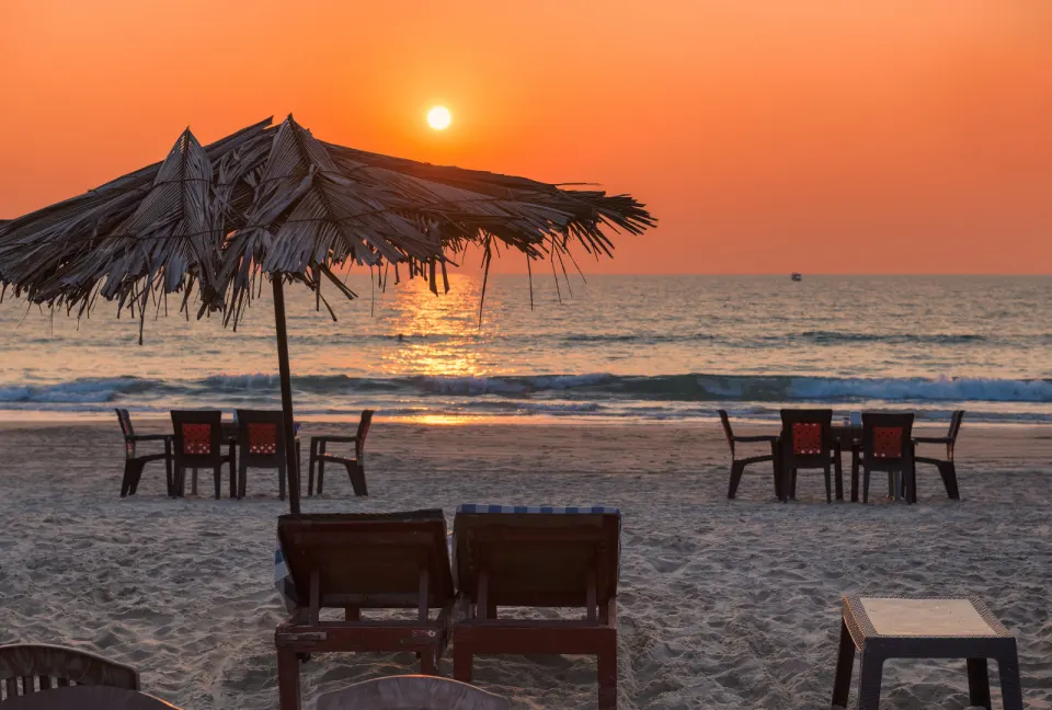beach umbrellas silhouetted against a sunset over the Arabian Sea