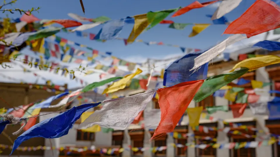Colorful Buddhist prayer flags strung across a monastery courtyard in Ladakh