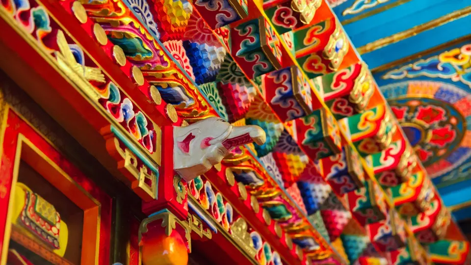 Carved wooden eaves painted in traditional colors at a Ladakhi monastery