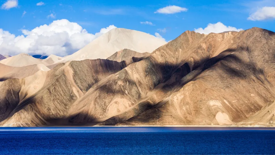 Mountain slopes reflected in the deep blue waters of Pangong Lake