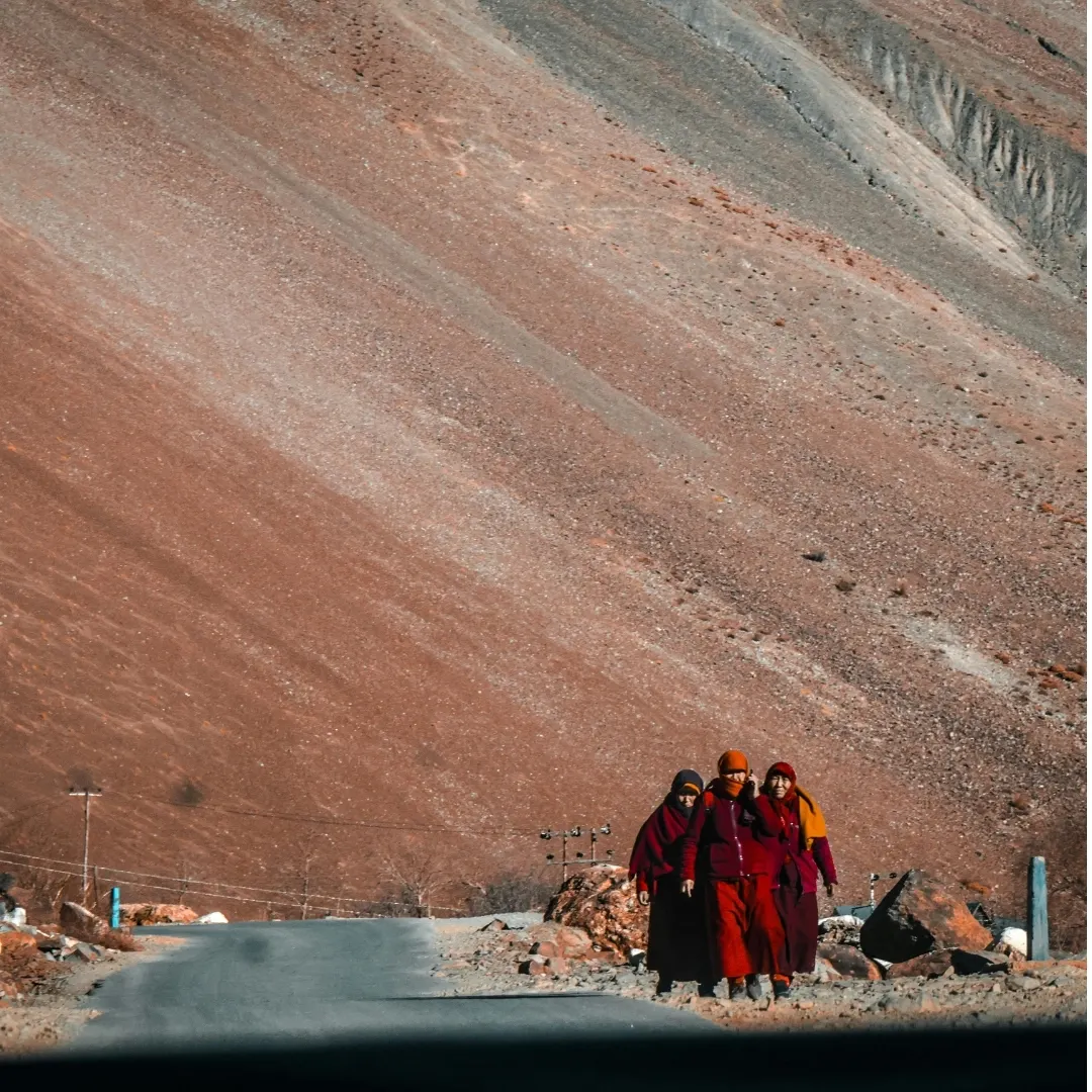 Buddhist monks walking along a remote mountain road in Ladakh