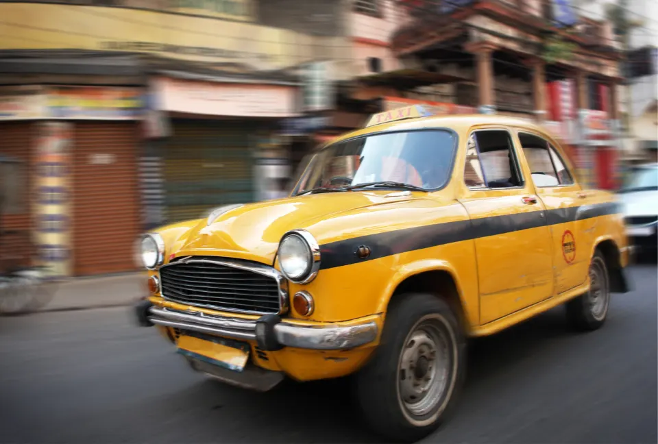 yellow ambassador taxi driving on a kolkata street