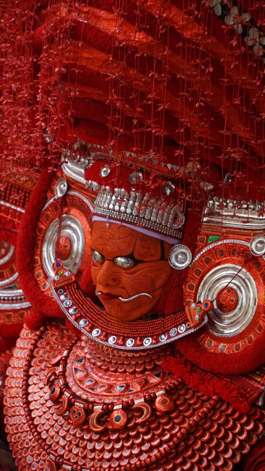 Kathakali performer in traditional red makeup and headgear
