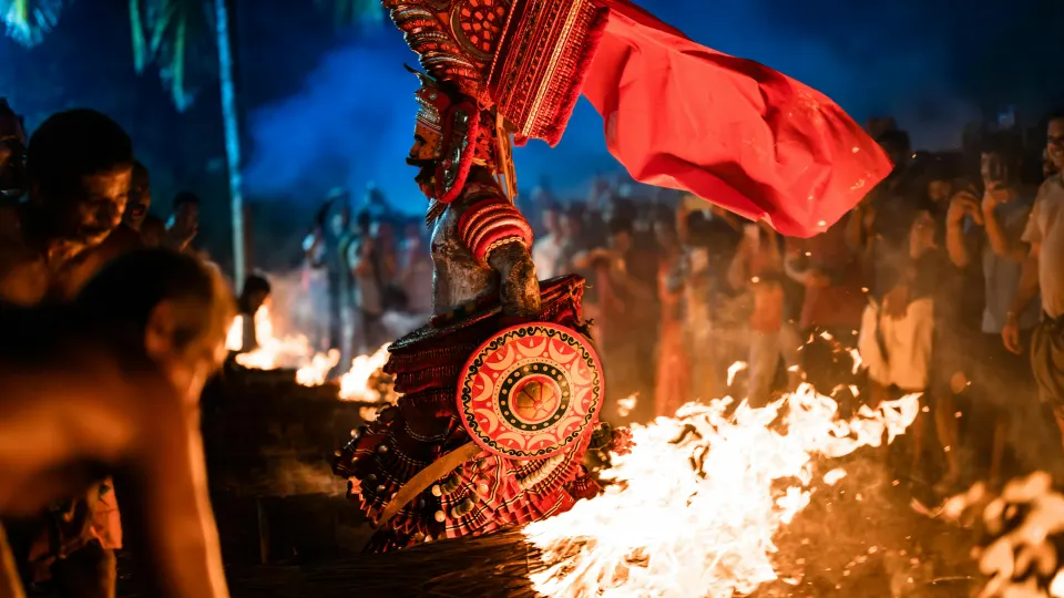 Theyyam ritual performer with fire during a traditional temple ceremony in Kannur, Kerala