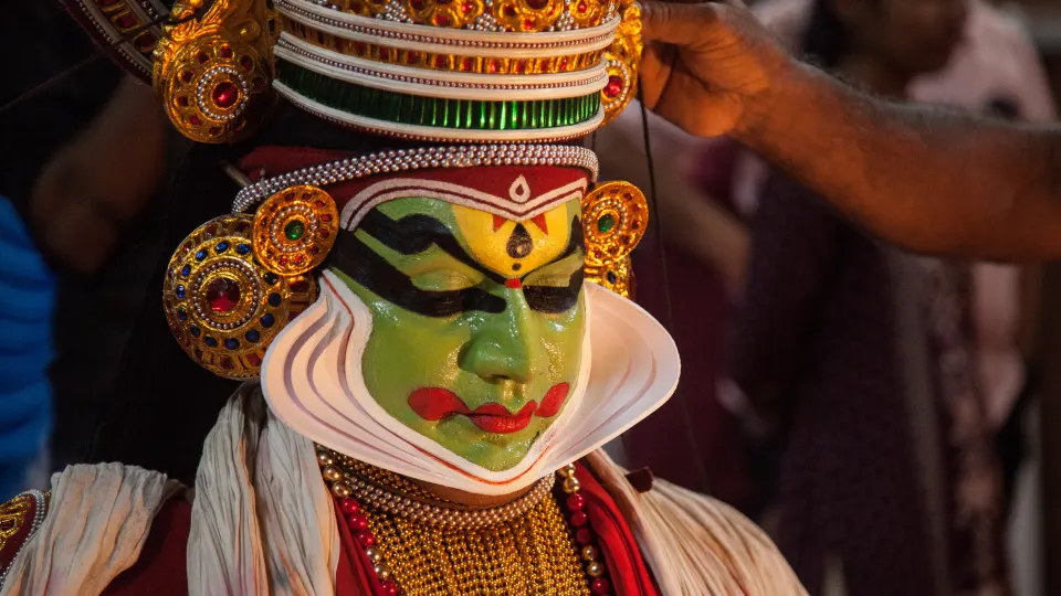 Kathakali performer with traditional green facial makeup and headgear