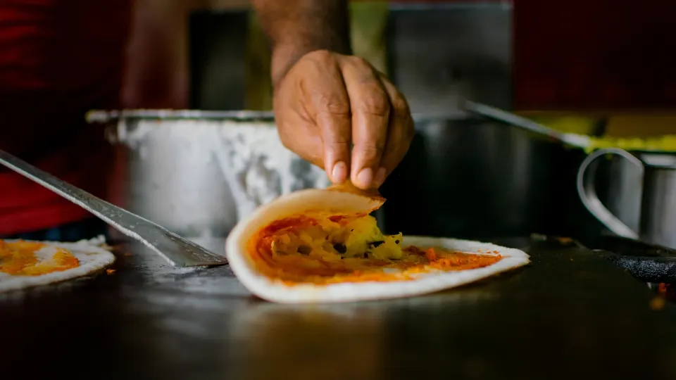 dosa being folded on hot griddle during street food preparation