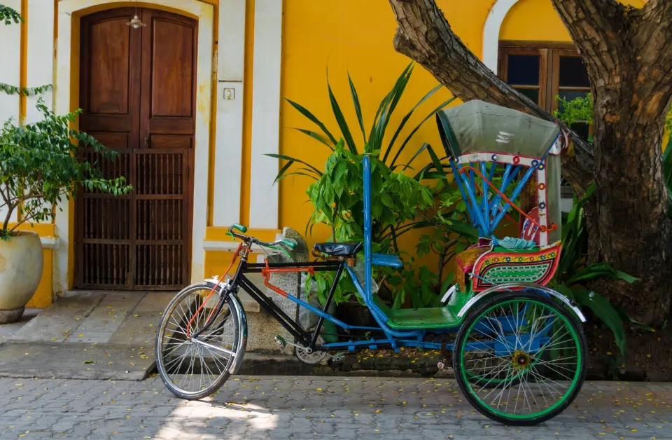 A colorful cycle rickshaw parked beside a yellow colonial building in Pondicherry’s White Town