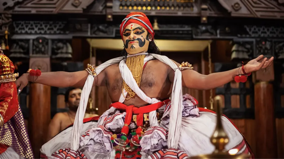 A Kalaripayattu performer in traditional costume striking a dramatic pose