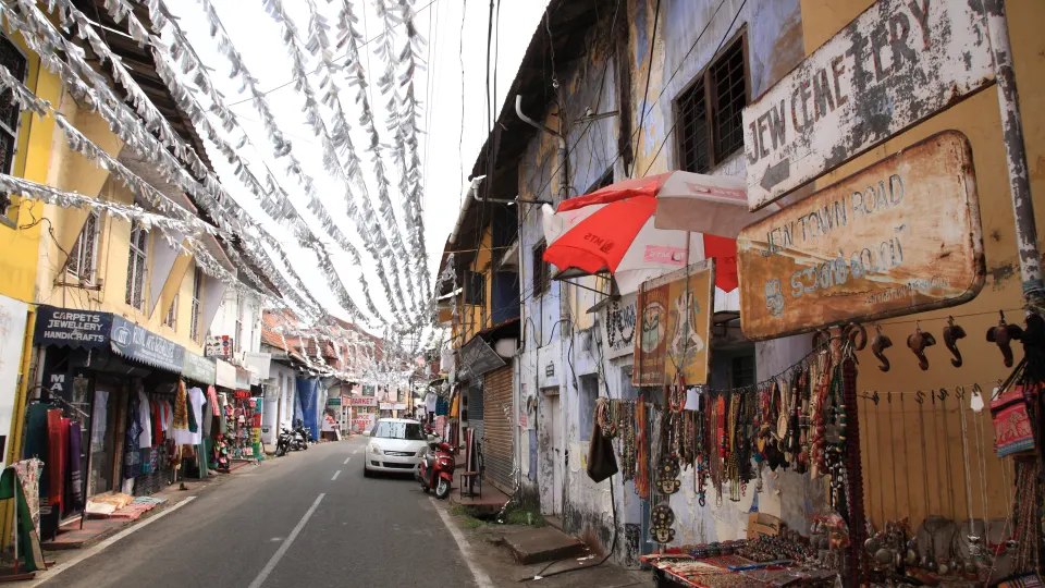 A narrow Fort Kochi street lined with shops, handicrafts, and hanging decorations