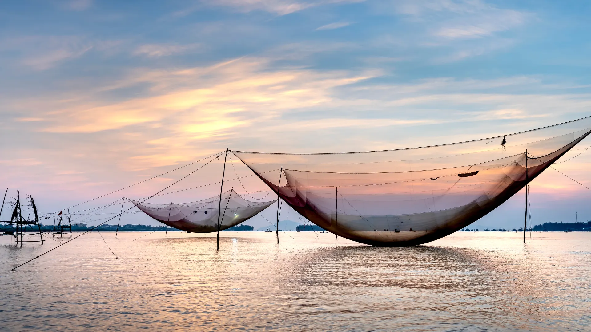 Chinese fishing nets over calm water during a colorful sunset