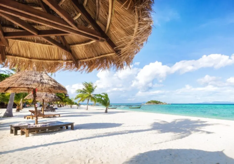 Beachfront wooden huts with thatched roofs overlooking a white sandy Lakshadweep beach and turquoise water