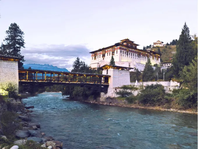 Paro Rinpung Dzong above a river with a traditional covered bridge