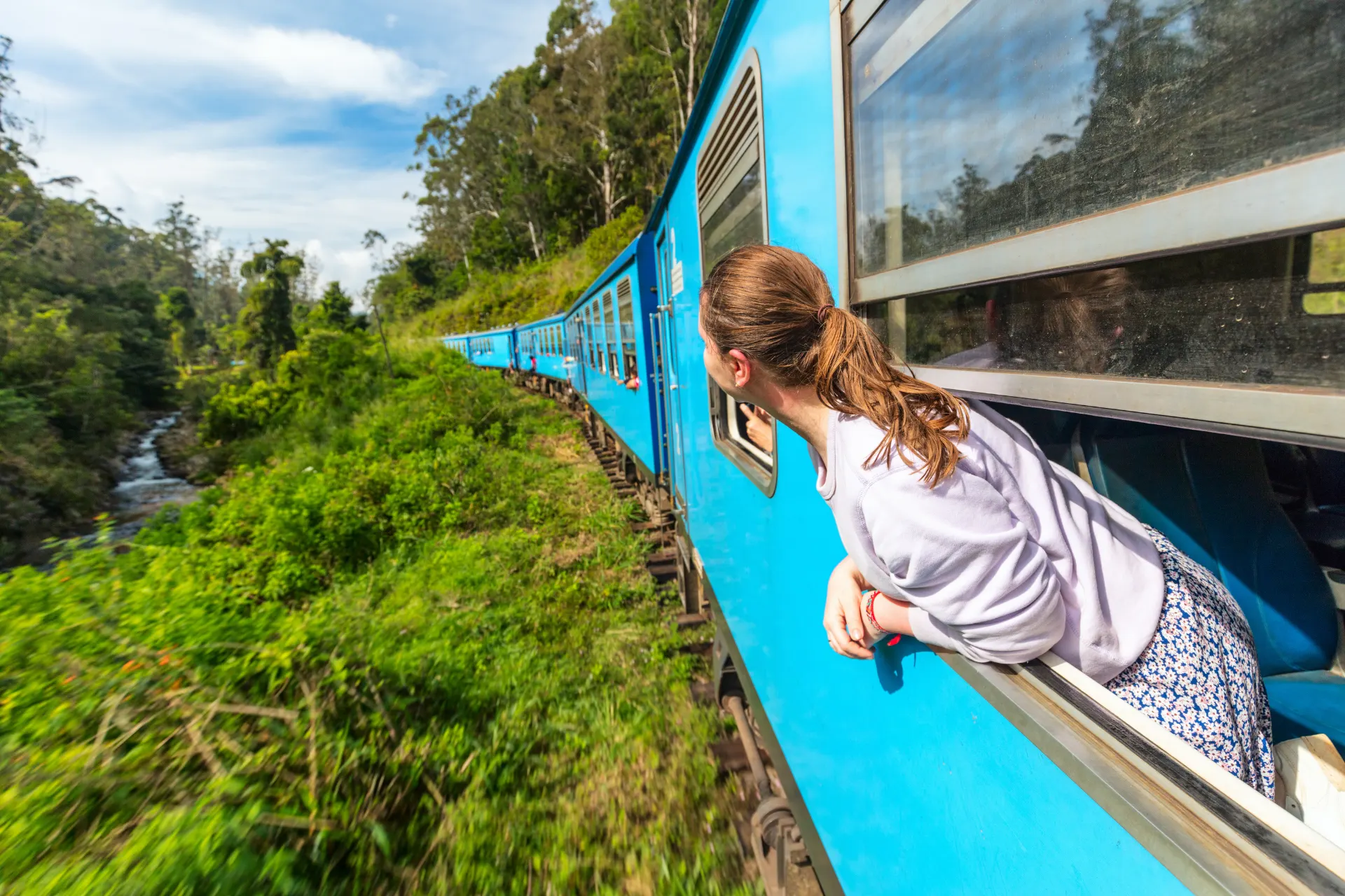 Traveller looking out from a blue train in Sri Lanka’s hill country
