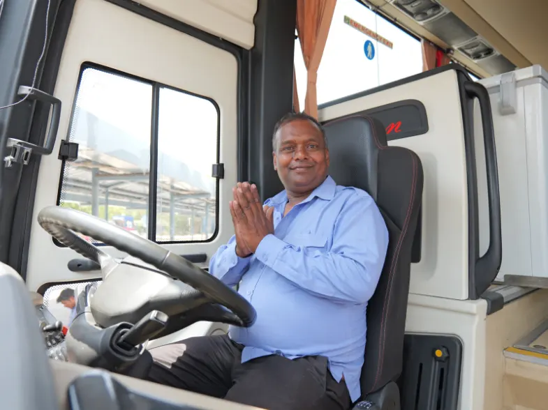Farbound coach captain greeting guests from the driver’s seat of a private tour bus in India