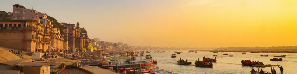 Boats on the Ganges River at sunset beside the ghats of Varanasi