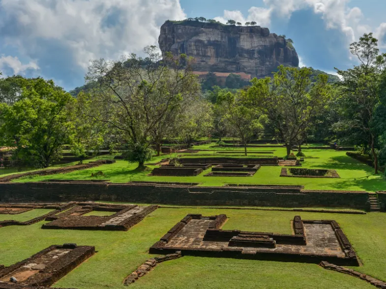 The sheer granite face of Sigiriya rock fortress rising from flat green dry-zone forest